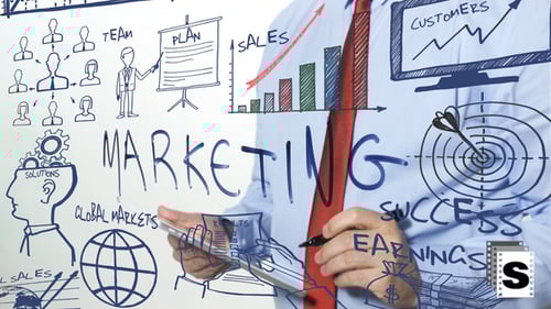 Man Drawings Marketing Plans on Glass Wall