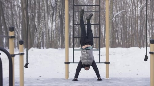 Man Doing Handstand in Snowy Winter Park