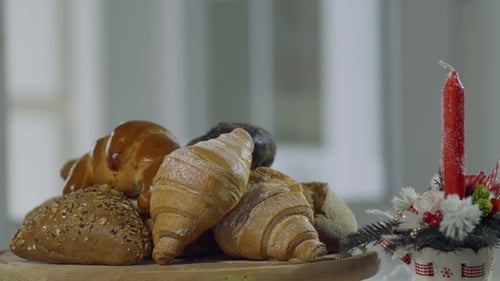 Bread and Sweet Baking Are Spinning Near Decorative Candle on Table