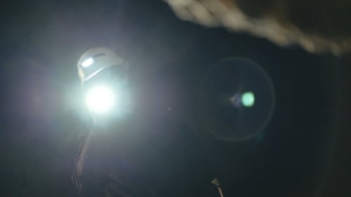 The Speleologists with Flashlight Exploring the Cave with Fear