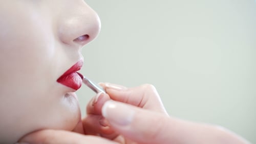 d'une jolie beauté maquillée. Femme appliquant Red Lip