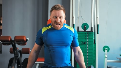 Muscular Man Doing Exercises with Dumbbells at Biceps in Gym