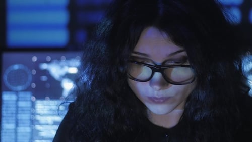 Une programmeuse hacker à lunettes travaille sur un ordinateur dans un centre de cybersécurité