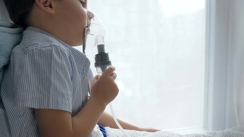 Diseased Boy Breathes through an Inhaler for Treatment in Hospital