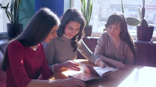 Friends Choosing Food From Menu in Restaurant