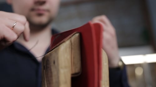 Man Creates a Brown Leather Wallet with His Own Hands with a Needle in the Leather Workshop,