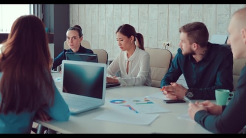 Woman Talking To Colleagues at a Meeting, Sitting at a Table in the Office