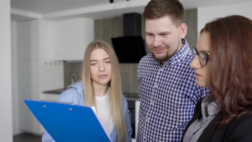 Abogada agente inmobiliaria muestra papel por comprar un apartamento para clientes, hombre y mujer