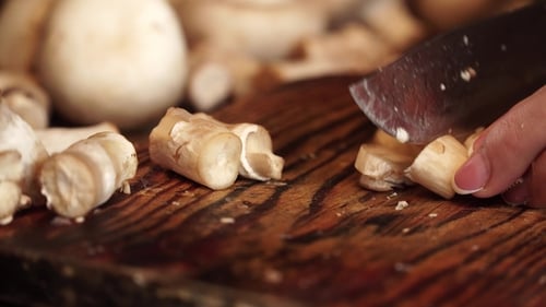 Person Chopping Mushrooms on Wooden Cutting Board