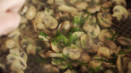 Woman Shuffles Herby Mushrooms on Hot Pan in Kitchen