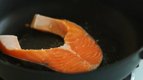 Close Up Salmon Cooking in Black Pan
