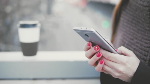Young Woman Uses a Smartphone in the City