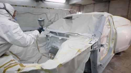 Man Spray Painting Car in Protective Suit