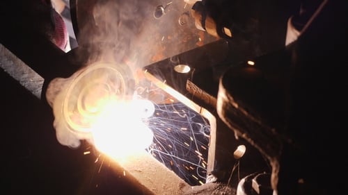 Welder Working on Metal in Dark Workshop