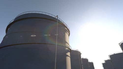 Industrial Storage Tanks at Sunrise with Sun Flare