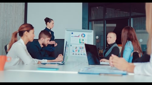 Businessman Makes a Presentation for Colleagues in the Office, Showing Charts on a Flipchart