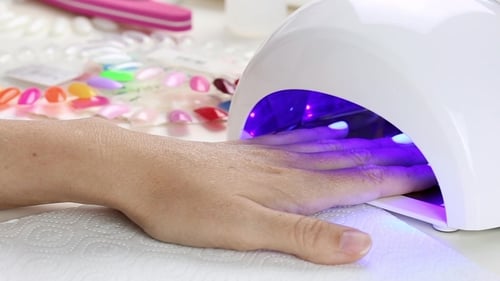 Woman Curing Gel Nail Polish with UV Light