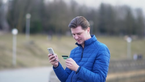 Mann tätigt Einkäufe mit Kreditkarte und Telefon