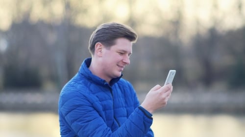 Adult Using Mobile Phone Outdoors in City Park