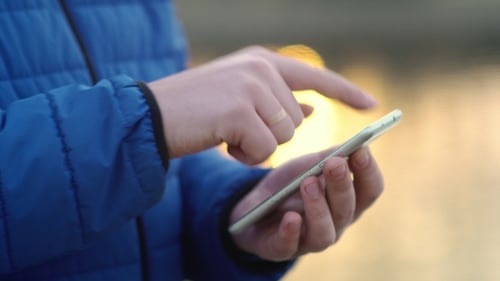 A Young Attractive Man Is Using a Mobile Phone at Sunset