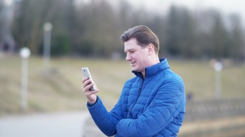 A Young Attractive Man Is Using a Mobile Phone at Sunset