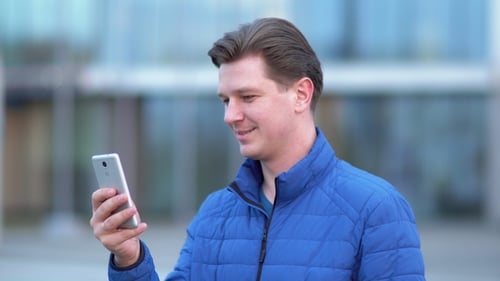 Ein junger attraktiver Mann benutzt bei Sonnenuntergang ein Handy