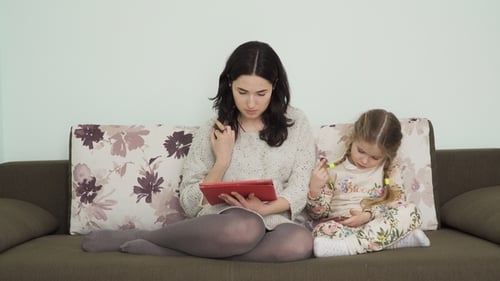Woman and Child Using Technology on Couch