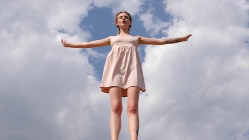 Young Woman Standing with Arms Outstretched in Daytime