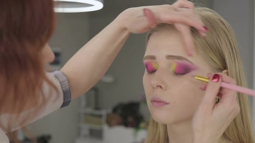 Applying Bright Makeup to Woman in Salon