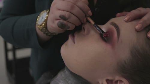 Makeup Artist Applying Glitter Eyeshadow to Young Woman