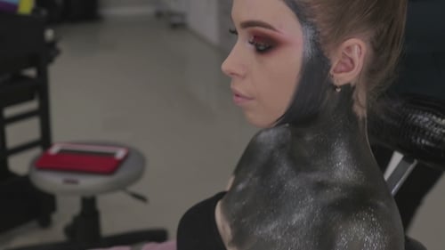 Woman Getting Black Glitter Makeup Applied in Studio