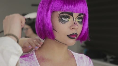 Stylist Combs Wig on Person with Creative Makeup