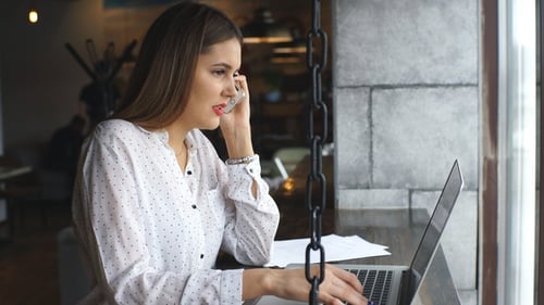 Young Woman Working on Laptop and Talking on Phone