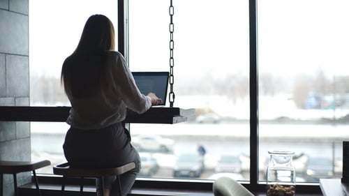 Confident Attractive Woman in a White Shirt Working in the Cafe with a Laptop
