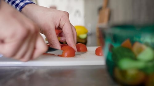 Crop Unrecognizable Man Standing at Table on Kitchen and Chopping Tomato on Cutting Board