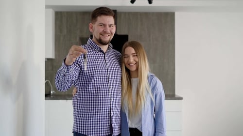 Happy Couple with Keys Embracing in New Home