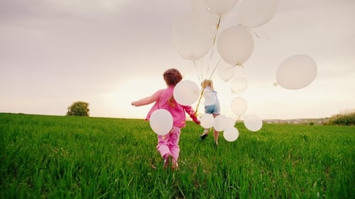 Two Carefree Little Girls Are Happy with the Arrival of Spring, They Run Along a Green Meadow with
