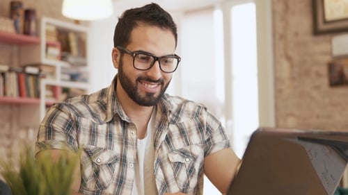 Man Smiling Typing on Laptop Indoors Close Up