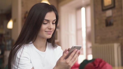Smiling Woman Using Phone Indoors