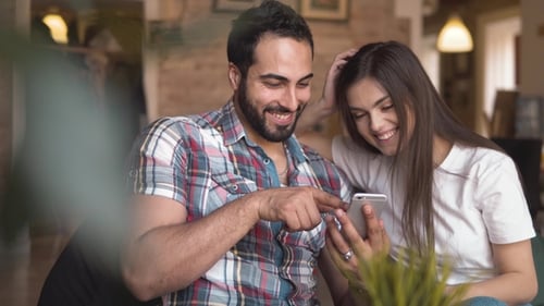 Happy Couple Using Smartphone Together Indoors