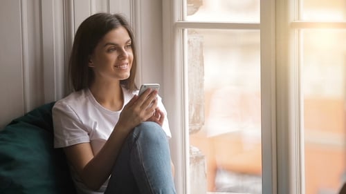 Woman Using Smartphone by Sunny Window