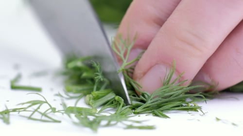 Cutting a Dill with a Knife. White Background
