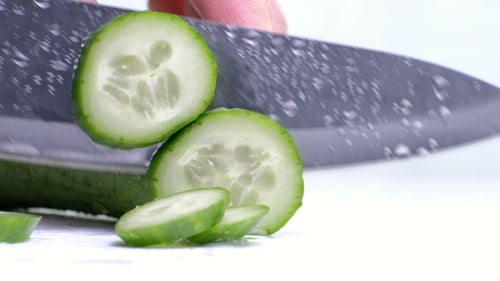 Cutting Raw Green Cucumber on a White Background.