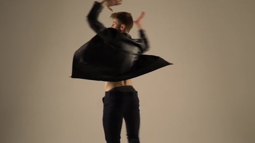 A Ballet Dancer in a Leather Jacket Shows a Fuette in the Studio,