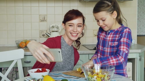 Smiling Woman and Child Making Salad Together
