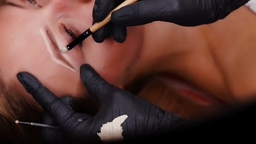 Slide View. Professional Specialist of Permanent Make-up in Black Gloves Paint Eyebrows.