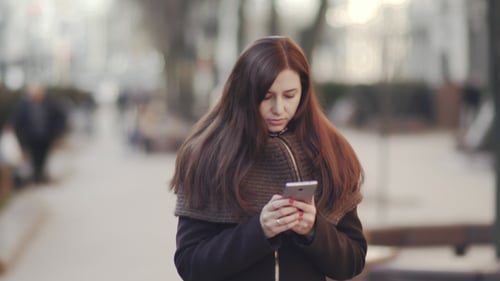 Young Attractive Woman Is Using a Smartphone in a Big City at Sunset