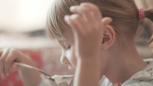 Young Girl Eating Food with Spoon, Close Up