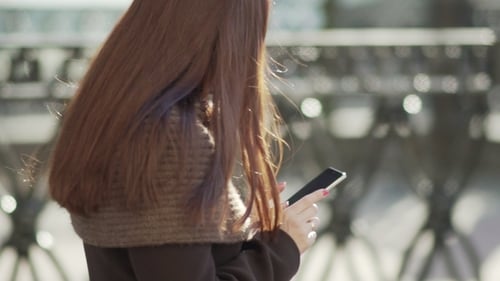 Young Attractive Woman Is Using a Smartphone in a Big City at Sunset