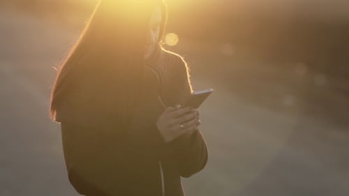 Woman Using Phone in Golden Sunlight